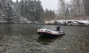 Bathymetric survey in zodiac in shallow river with light snowfall